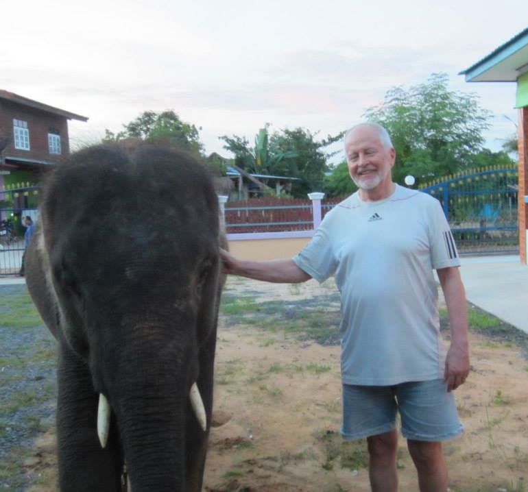 Photograph of Dave Hopkins with an elephant at home in Thailand